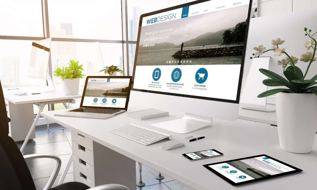 „Kontorarbeidsplass med flere skjermer som viser responsiv nettside – symbol for profesjonell webdesign.