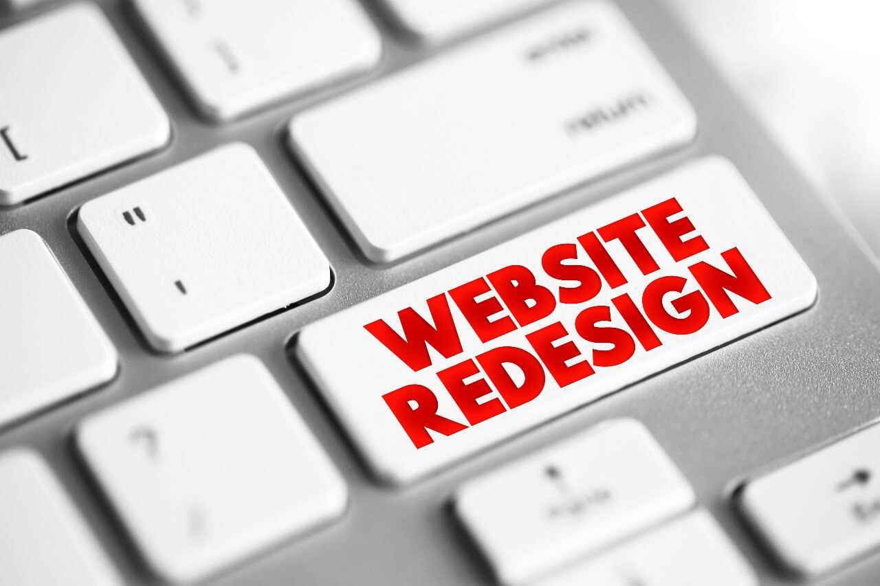 Tastatur med rød knapp 'WEBSITE REDESIGN' – symbol for nettsideoppgradering.